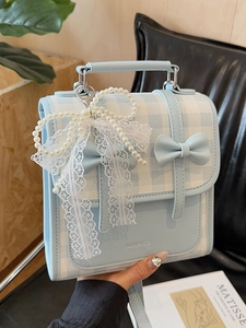 Mini sac à dos à carreaux bleu clair avec nœud et pendentif perle tenu à la main