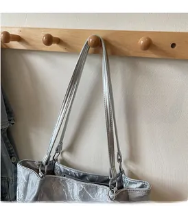 Macro view of silver crinkled metallic tote bag with long handles and zipper closure