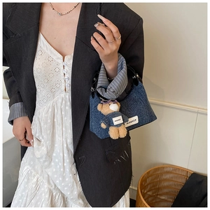 Détail du sac seau en denim bleu avec breloque ours et fond de panier en osier