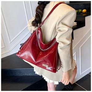 Close-up of deep red glossy tote bag with silver chain and heart lock on leather