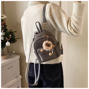 Grey mini backpack with lion plush charm detail shown in a cozy indoor lifestyle scene