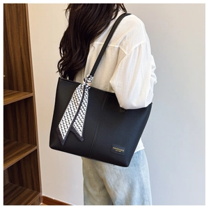 Détail du sac cabas en cuir noir avec foulard en soie porté par un mannequin