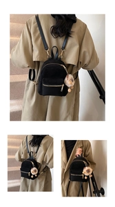 Close-up of black mini backpack with gold zippers and a plush lion charm detail