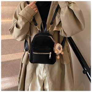 Detailed view of mini black faux suede backpack with gold hardware and plush charm on side
