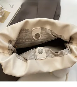 Detail of cream leather bucket bag showing magnetic closure and herringbone lining