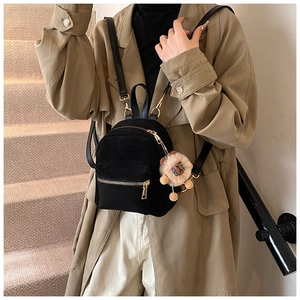 Close-up of black mini backpack with gold zippers and a plush lion charm decoration