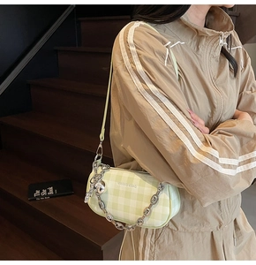 Gros plan du sac sous le bras à carreaux vert clair avec chaîne argentée et pendentif