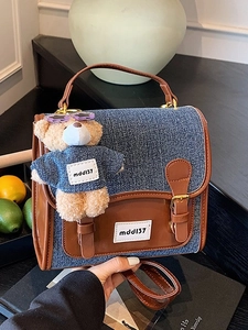 Retro denim backpack with brown leather trim and cute bear charm in a lifestyle setting