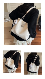 Detail view of large cream tote bag with silver butterfly accent and plush cloud charm