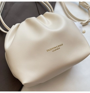 Close-up of cream leather bucket bag showing gold printed text and drawstring texture