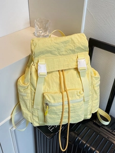 Minimalist light yellow large capacity travel backpack on a black suitcase in a modern room