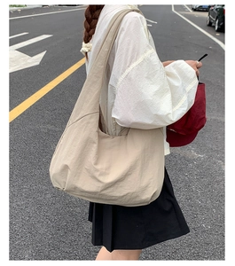 Street view of large khaki tote bag with wide strap and water-resistant nylon texture