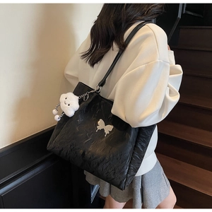 Detailed view of black pleated tote bag with silver butterfly buckle and cloud charm