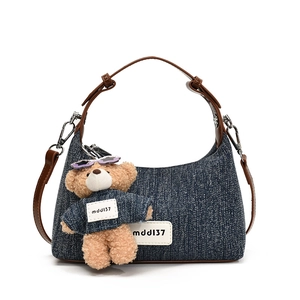 Blaue Jeans-Schultertasche mit braunem Gurt und Plüschbär-Anhänger auf weißem Hintergrund