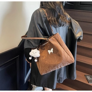 Detail of a large brown tote bag with butterfly accents and plush cloud charm
