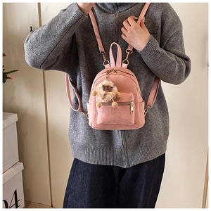 Detailed close-up of pink mini faux suede backpack with plush lamb charm and gold zippers
