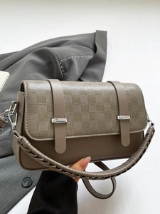 Braune Handtasche mit Schachbrettmuster und geflochtenem Griff auf grauem Blazer