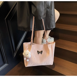 Close-up of pink butterfly tote bag with cloud plush charm on wooden stairs
