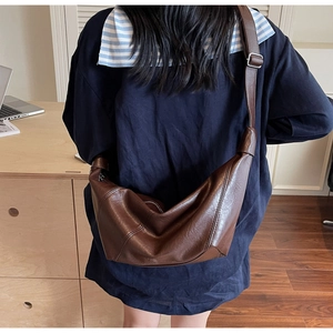 Detail of soft dark brown crescent bag with wide adjustable strap and silver metal buckle