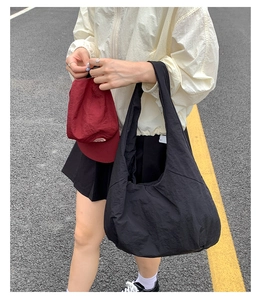 Street style view of the large black waterproof nylon tote bag on a fashion model