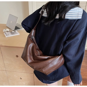 Detail of soft brown PU leather shoulder bag with natural pleats and wide strap