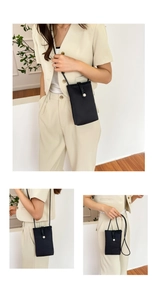 Detail of black drawstring crossbody phone bag with a white flower pendant