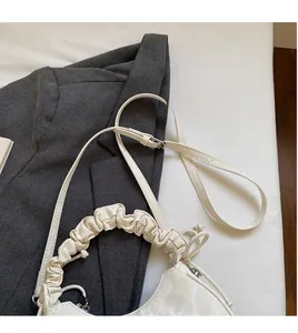 Détail du sac à main plissé blanc cassé avec bandoulière réglable et ferrures métalliques
