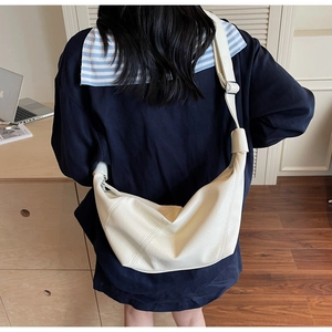 Detail of off-white soft PU leather shoulder bag with adjustable strap on a model