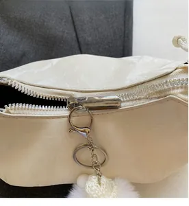 Détail du zip argenté et charme en maille blanche sur un sac à bandoulière crème