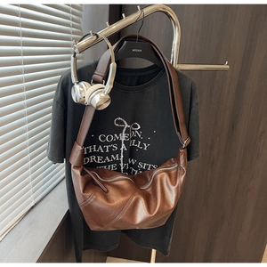 Detail view of large dark brown soft leather dumpling bag with wide strap and silver zipper