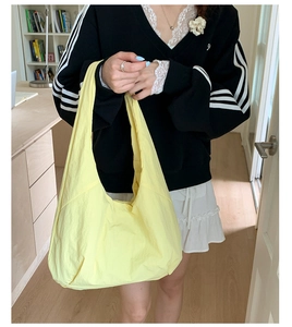 Detailed view of large yellow crescent tote bag with lightweight pleated nylon texture