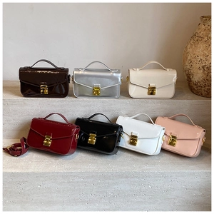 Selection of glossy patent leather chain crossbody bags in seven elegant colors on stone surface