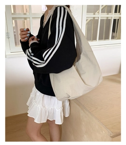 Detail of a beige large capacity tote bag with wide shoulder strap on a female model