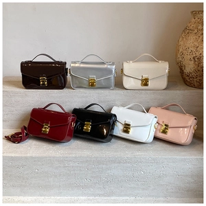 Detailed view of assorted colors of glossy patent leather mini chain bags on stone steps