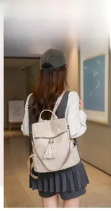 Detail of light beige PU leather backpack with tassel zippers shown on a model
