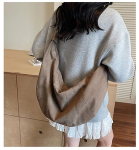 Rear view of model wearing a large brown canvas dumpling bag with wide shoulder strap