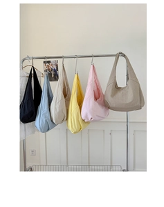 Row of colorful large nylon hobo bags in blue, pink, and yellow on metal hangers