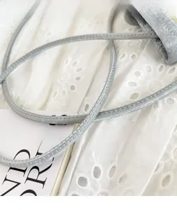 Detail of grey crossbody bag strap featuring crackle texture and fine stitching