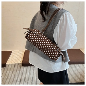Detailopname van een bruine baguette-tas met stippen gedragen door een model