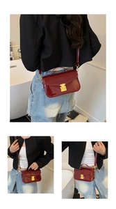Detail of red patent leather crossbody bag with gold metal clasp and top handle