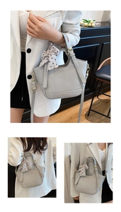 Détail du sac seau en cuir gris clair avec motif litchi, nœud à pois et bandoulière