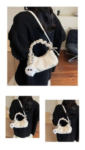 Détail du sac hobo plissé ivoire avec breloque en peluche et logo de mode élégant