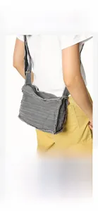 Detail of grey canvas crossbody bag with frayed edge design and adjustable wide strap