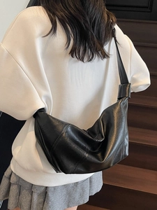 Minimalist black soft leather hobo bag for women worn as a crossbody shoulder bag