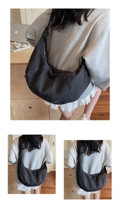 Detail of black canvas crescent bag with unique knot shoulder strap and pleated texture