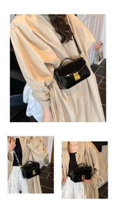 Detail of black patent leather crossbody bag with gold metallic buckle and chain strap