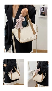Détail du sac seau en cuir grainé avec poignées marron et un nœud décoratif rose