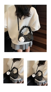 Détail d'un sac à main plissé noir avec un charme de monstre en peluche blanc et texture