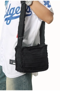 Detail of black canvas crossbody bag featuring multi-layer fringe and frayed edge texture