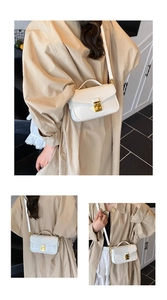 Close-up of a white patent leather crossbody bag with a gold metal square lock and handle